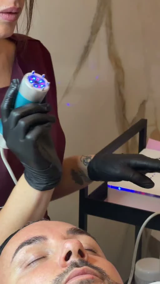 Un’operatrice utilizza uno strumento blu e bianco sul viso di un cliente